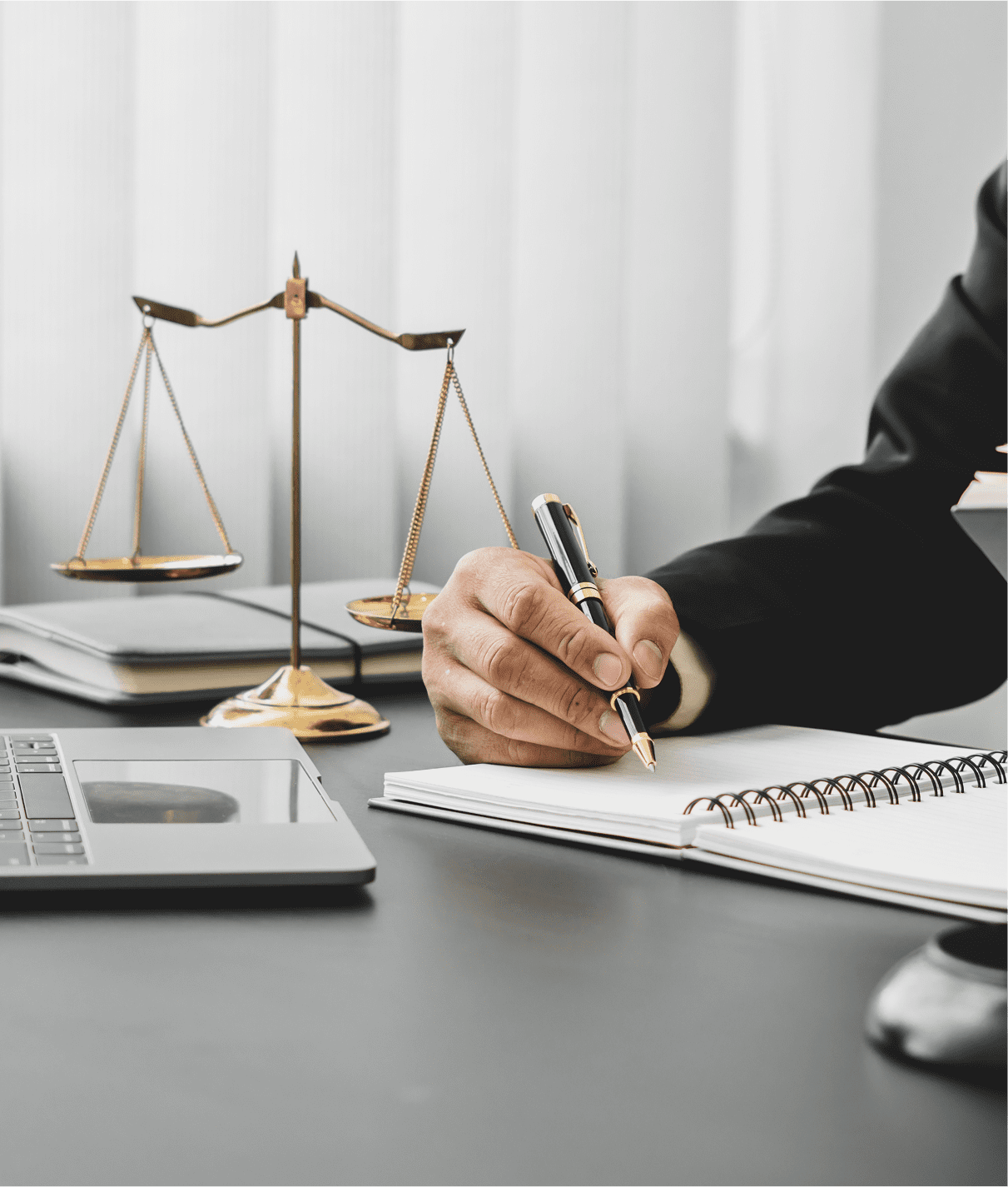 Person writing at desk with scales nearby.